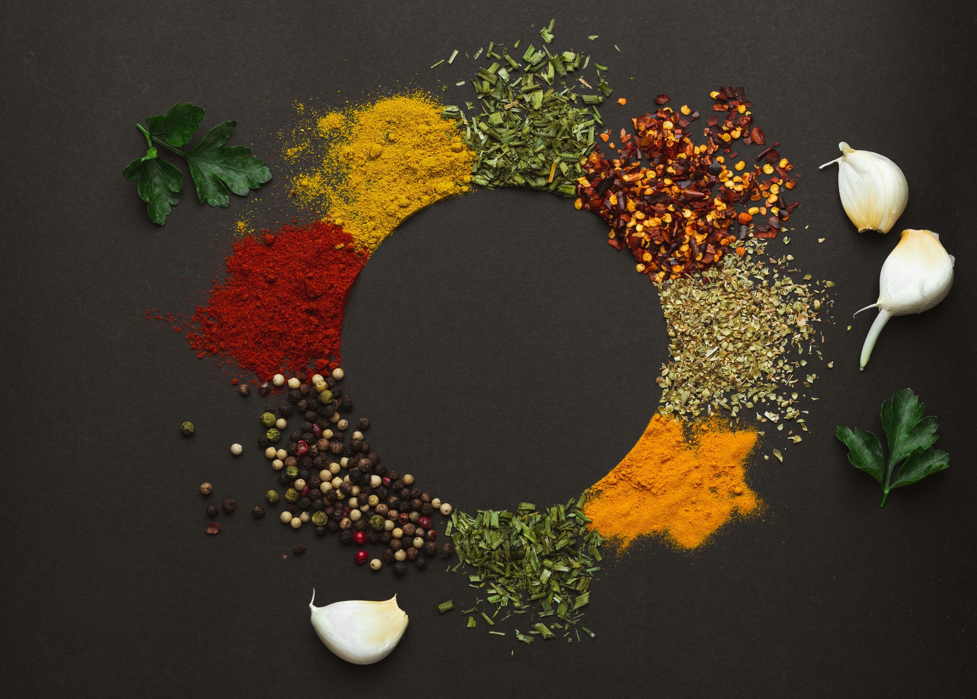 Circle frame composition of spices and herbs isolated on dark background with copy space. Frame of Indian spices and herbs. Ingredients of asian cuisine spices